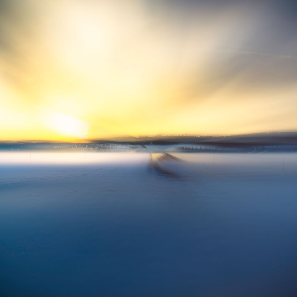 Image floue d'un paysage avec un ciel lumineux et des couleurs bleues et jaunes.