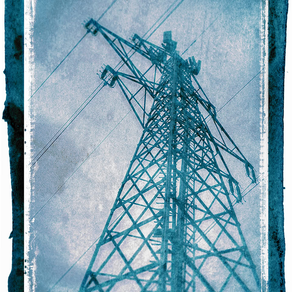 Tour électrique en métal vue en contre-plongée avec un ciel nuageux en arrière-plan, dans des tons bleus.