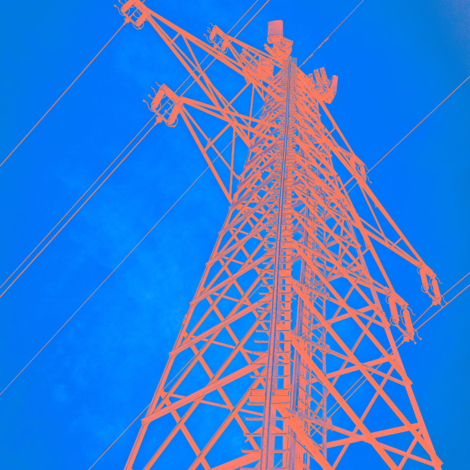 A tall electricity transmission tower against a bright blue sky.