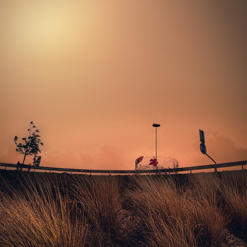 Paysage urbain avec herbes au premier plan, lampadaire et panneau routier sur une route, ciel brumeux et orangé.